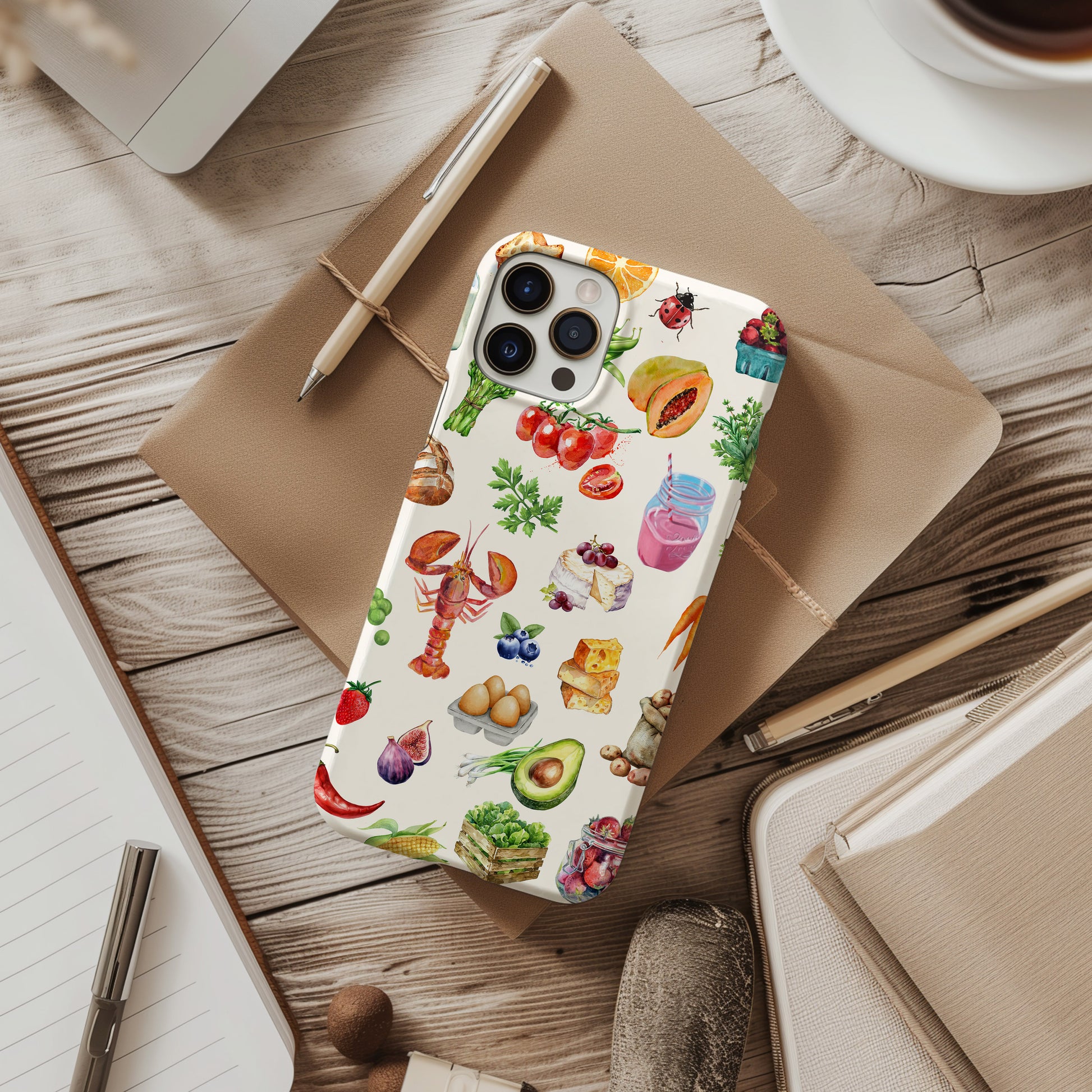 desk view of farmer's market collage phone case. Scrapbook watercolor style with images of farm fresh food on a crem background. Phone case for iPhone and Samsung by Artscape Market